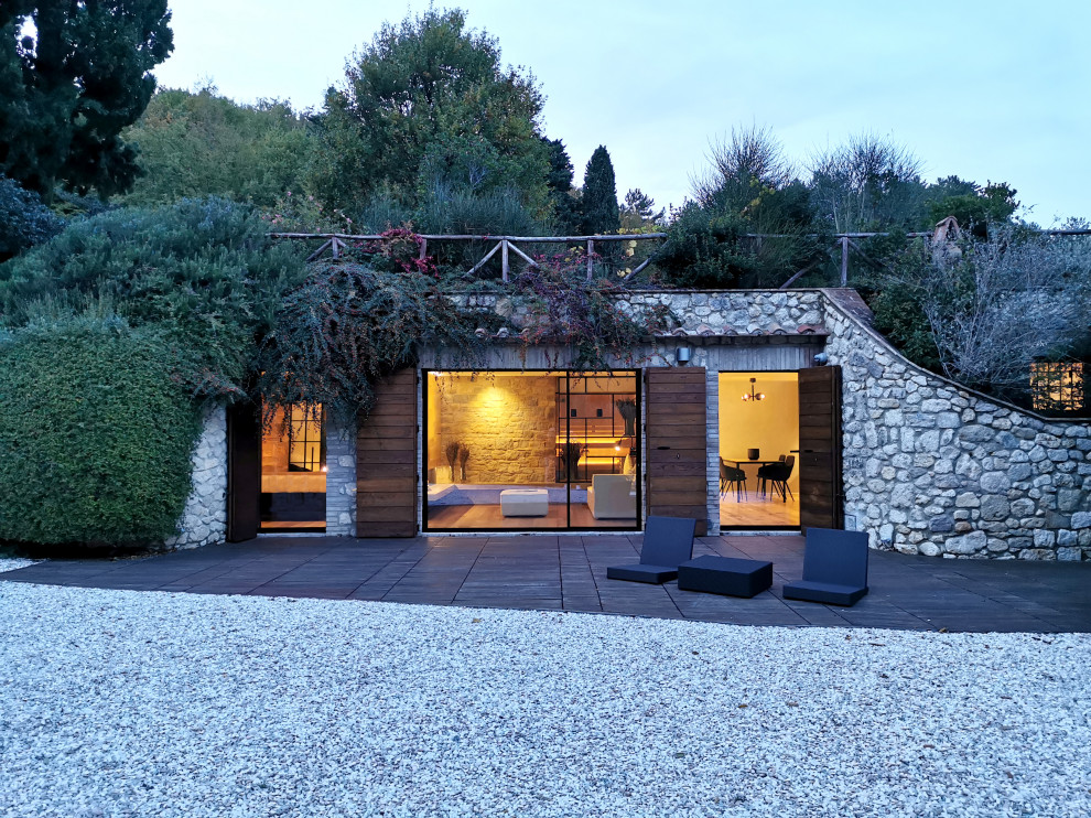 Design ideas for a small and gey rustic bungalow house exterior in Rome with stone cladding and a flat roof.