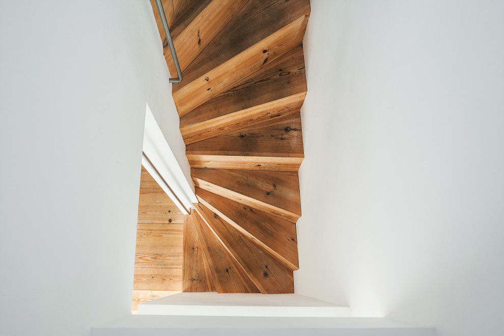 This is an example of a large contemporary wood u-shaped staircase in London with wood risers and metal railing.