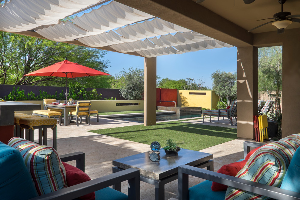 This is an example of a mid-sized contemporary backyard patio in Phoenix with a water feature, tile and an awning.