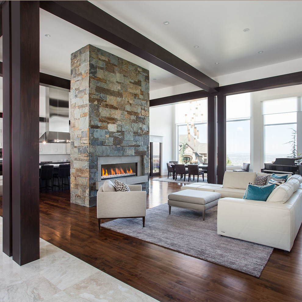 Inspiration for an expansive contemporary formal open concept living room in Salt Lake City with white walls, dark hardwood floors, a two-sided fireplace and a stone fireplace surround.