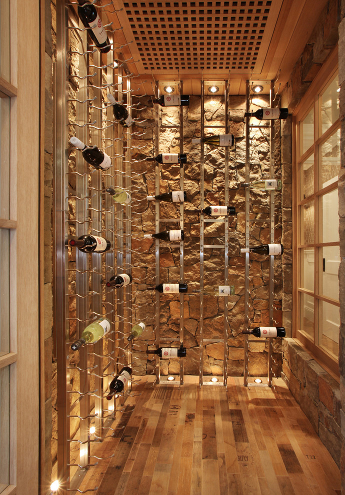 Photo of a beach style wine cellar in Orange County with medium hardwood floors, display racks and beige floor.