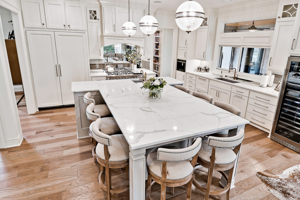Inspiration for a large transitional eat-in kitchen in Other with recessed-panel cabinets, white cabinets, quartzite benchtops, mirror splashback, stainless steel appliances, with island, white benchtop and light hardwood floors.