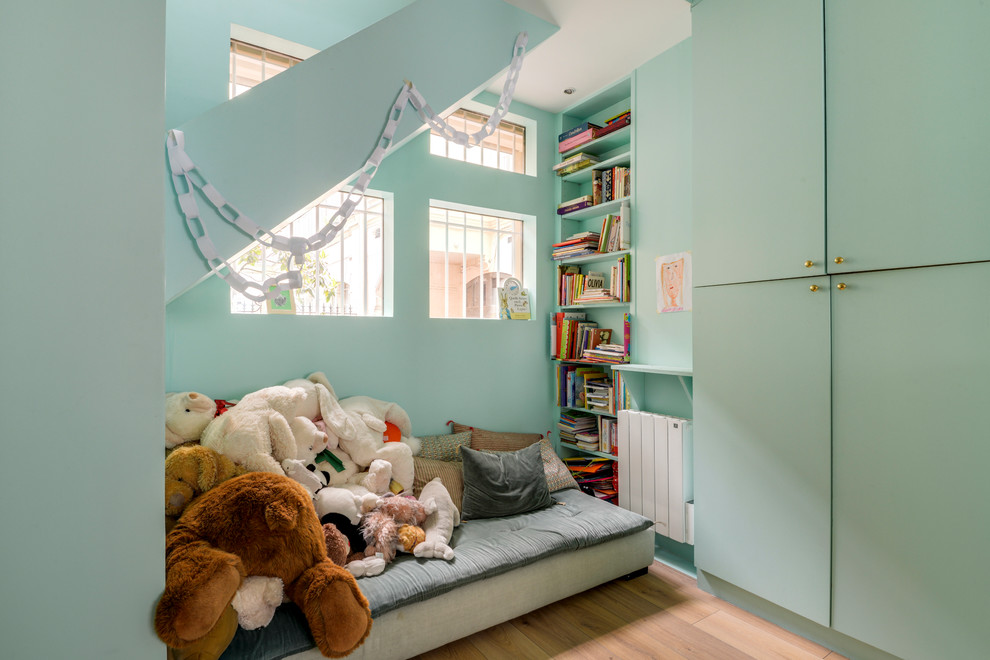 Eclectic gender-neutral kids' playroom in Paris with green walls and brown floor.