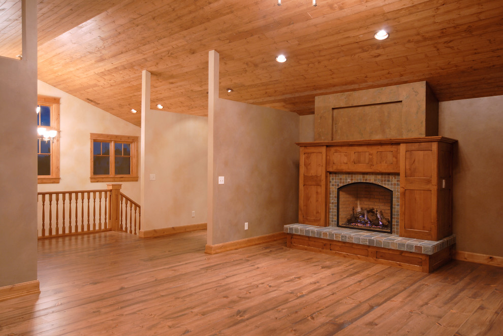 Mid-sized country open concept family room in Other with beige walls, medium hardwood floors, a standard fireplace, a tile fireplace surround, no tv and brown floor.