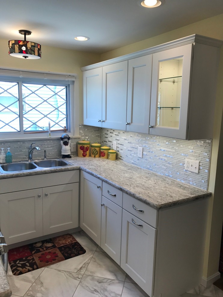 Enclosed kitchen - small transitional u-shaped limestone floor and gray floor enclosed kitchen idea with a drop-in sink, recessed-panel cabinets, white cabinets, laminate countertops, white backsplash, mosaic tile backsplash, stainless steel appliances and no island