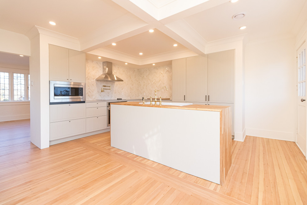 Inspiration for a mid-sized transitional l-shaped medium tone wood floor, brown floor and coffered ceiling eat-in kitchen remodel with a farmhouse sink, raised-panel cabinets, gray cabinets, wood countertops, beige backsplash, ceramic backsplash, stainless steel appliances, an island and brown countertops