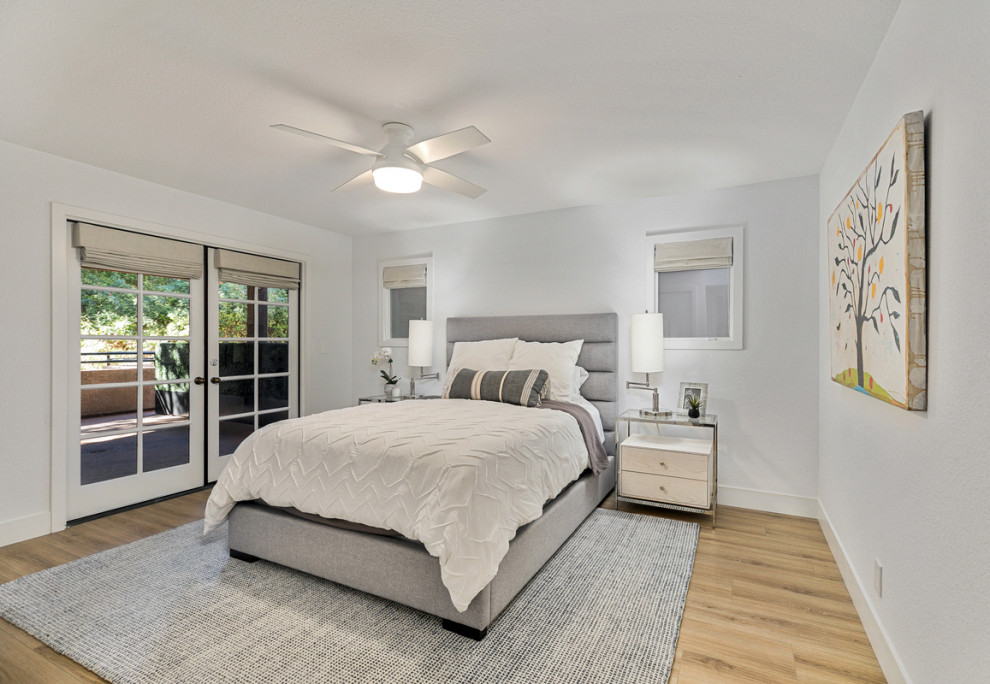 Small beach style master bedroom in Orange County with white walls, vinyl floors and brown floor.