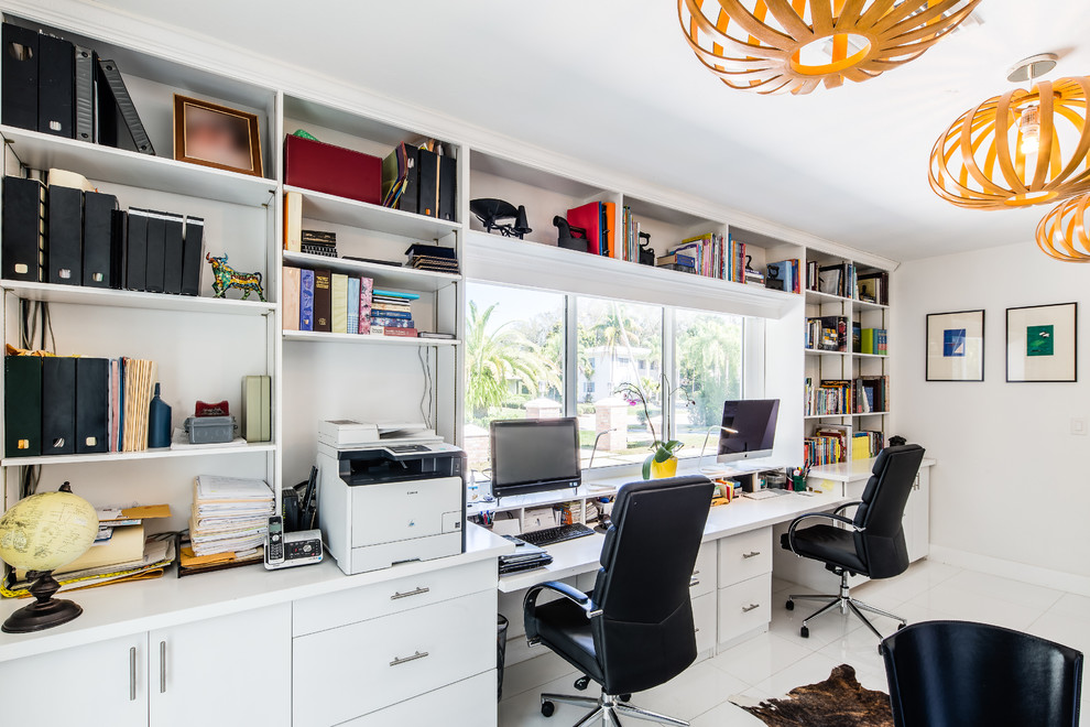 Photo of a large contemporary study room in Boston with white walls, concrete floors and a built-in desk.