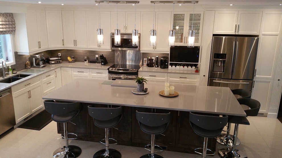 Photo of a large contemporary l-shaped open plan kitchen in Montreal with a double-bowl sink, shaker cabinets, white cabinets, granite benchtops, grey splashback, matchstick tile splashback, stainless steel appliances, ceramic floors, with island and grey floor.