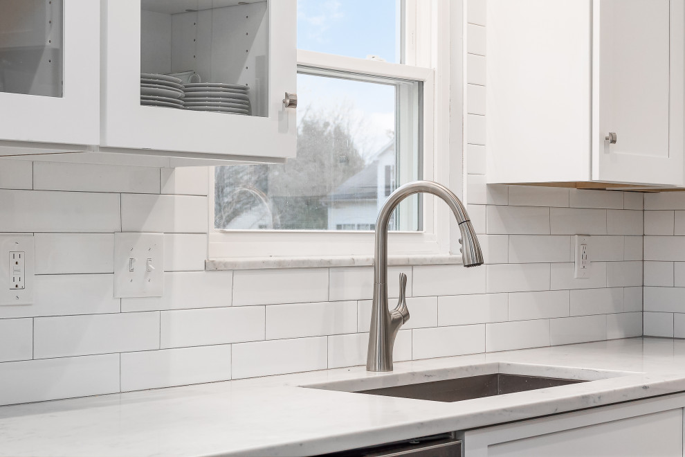 Example of a mid-sized transitional l-shaped eat-in kitchen design in Columbus with shaker cabinets, quartz countertops, white backsplash, subway tile backsplash and an island