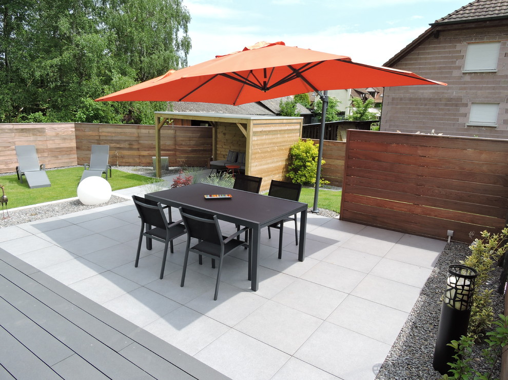 Design ideas for a mid-sized contemporary backyard patio in Strasbourg with a pergola.
