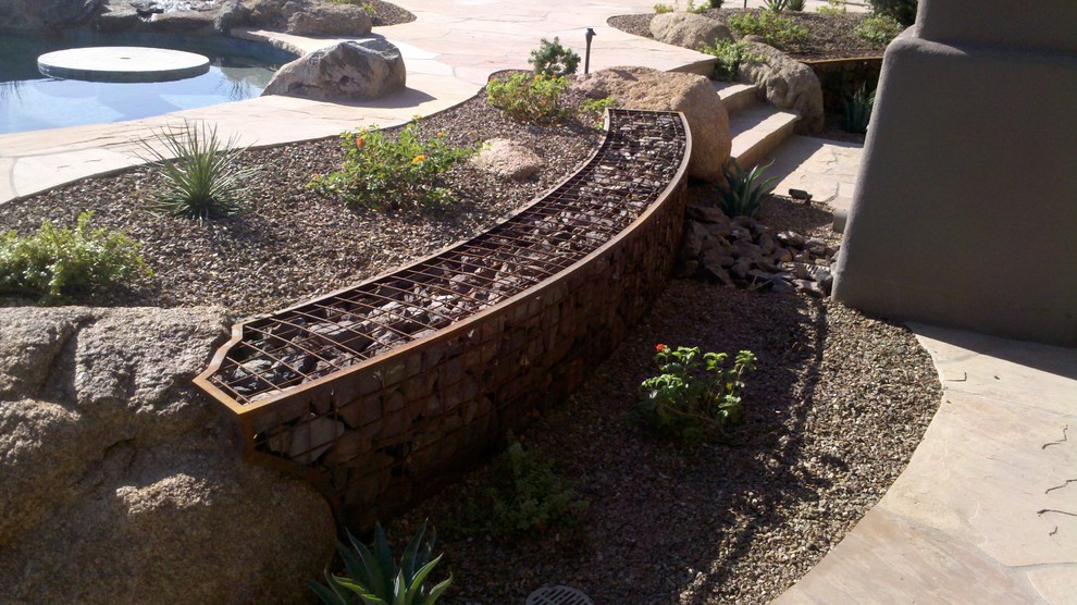This is an example of a large backyard full sun xeriscape in Phoenix with a retaining wall.