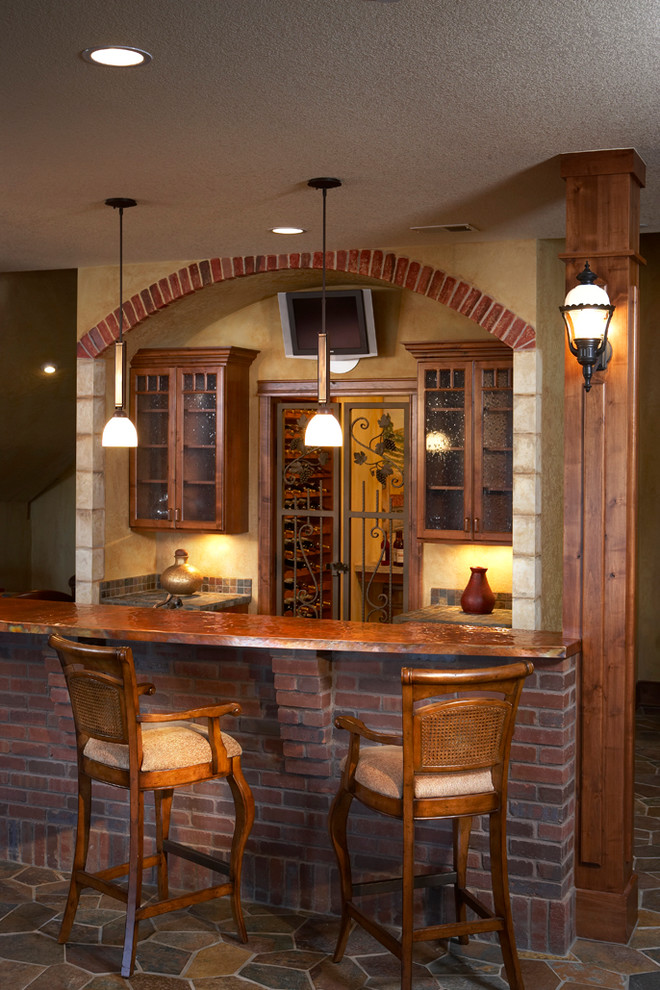 Photo of a large arts and crafts single-wall seated home bar in Denver with glass-front cabinets, dark wood cabinets, copper benchtops, multi-coloured splashback, stone tile splashback, slate floors and multi-coloured floor.