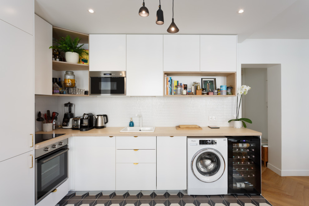 This is an example of a small scandinavian l-shaped open plan kitchen in Other with a drop-in sink, flat-panel cabinets, white cabinets, wood benchtops, white splashback, mosaic tile splashback, stainless steel appliances, cement tiles, no island, grey floor and beige benchtop.