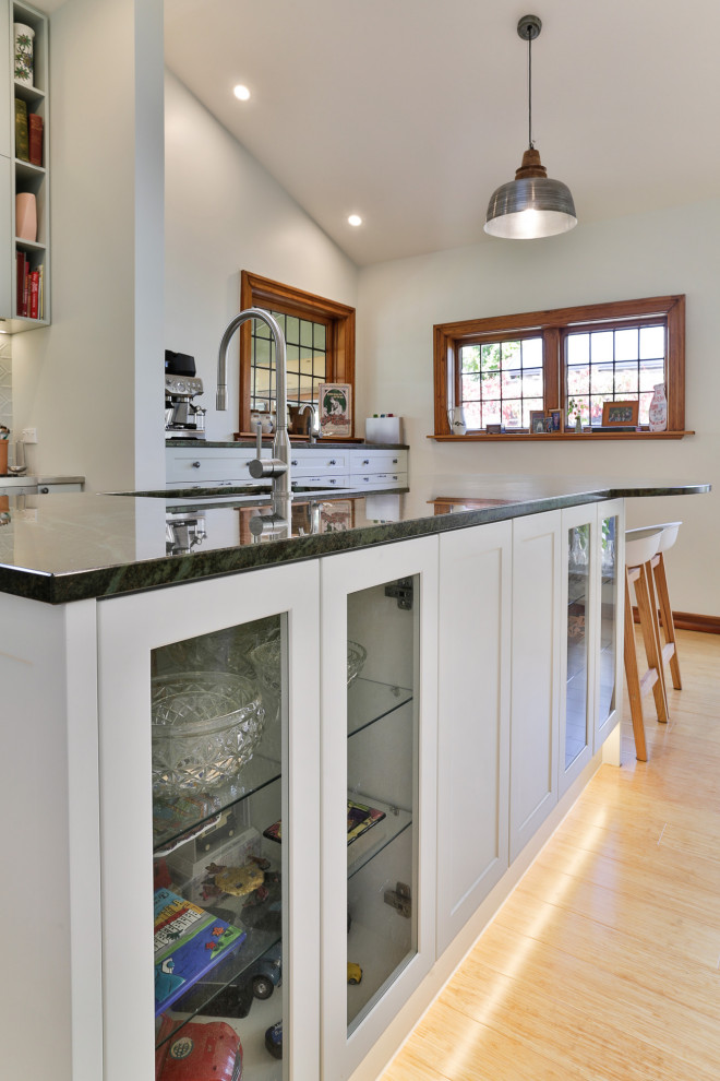 Design ideas for a large traditional l-shaped kitchen pantry in Christchurch with an undermount sink, shaker cabinets, green cabinets, granite benchtops, green splashback, metal splashback, stainless steel appliances, bamboo floors, with island and green benchtop.