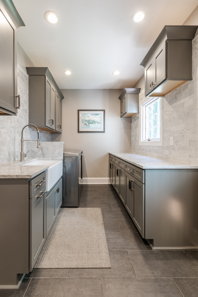 Inspiration for a mid-sized contemporary u-shaped utility room in DC Metro with a side-by-side washer and dryer, beaded inset cabinets, grey cabinets, grey splashback, grey walls, grey floor and grey benchtop.