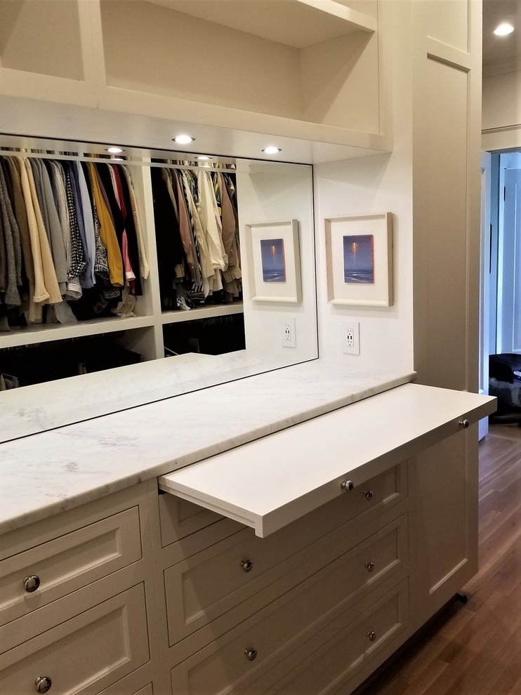 Large traditional gender-neutral walk-in wardrobe in Seattle with recessed-panel cabinets, white cabinets, light hardwood floors and brown floor.