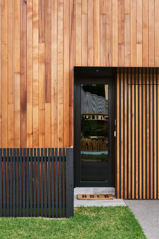 Contemporary two-storey black townhouse exterior in Geelong with wood siding, a gable roof and a metal roof.