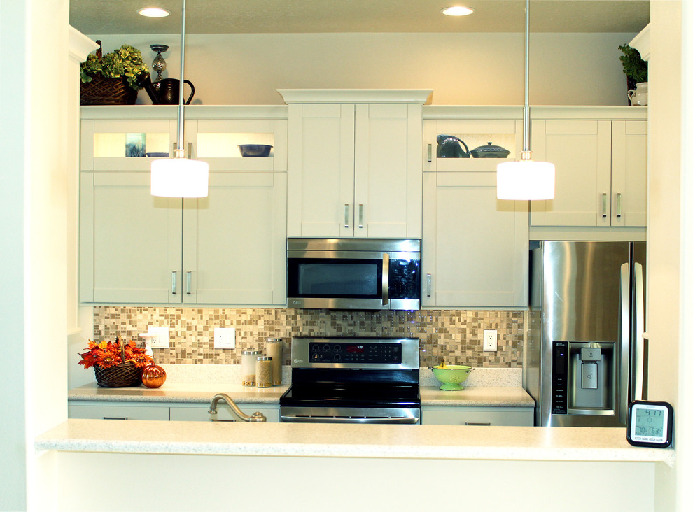 Example of a transitional galley eat-in kitchen design in Boise with an integrated sink, shaker cabinets, white cabinets, solid surface countertops, beige backsplash, glass tile backsplash and stainless steel appliances