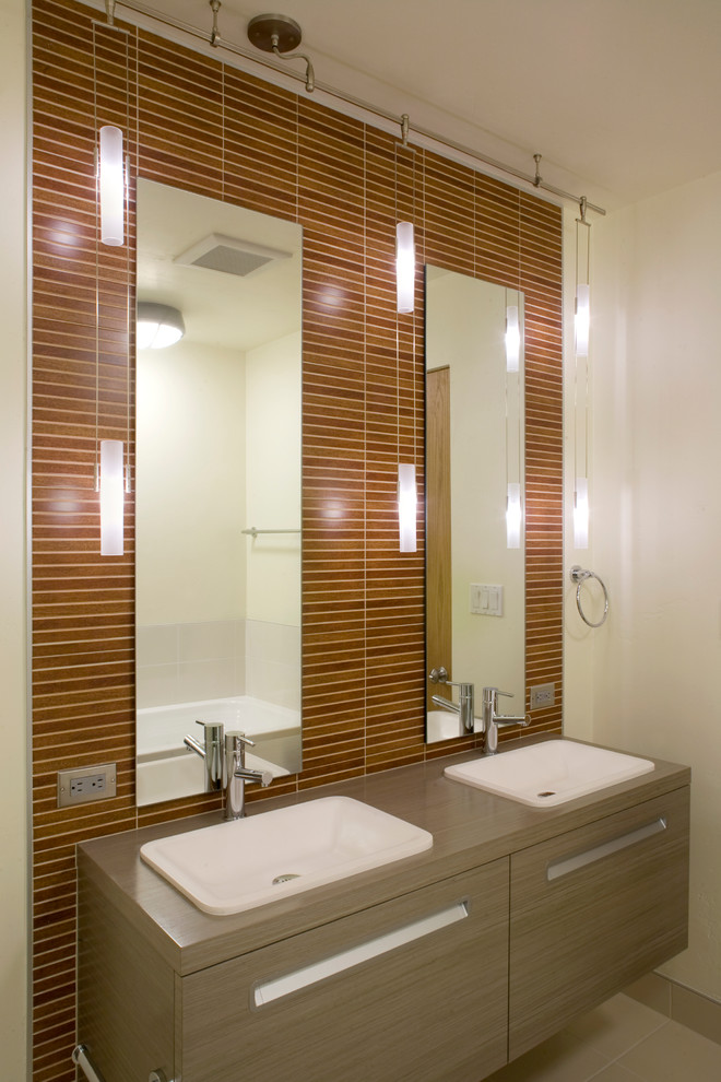 Inspiration for a mid-sized contemporary master bathroom in Denver with flat-panel cabinets, light wood cabinets, an undermount sink, a drop-in tub, brown tile, matchstick tile, solid surface benchtops, an alcove shower, a two-piece toilet, beige walls, ceramic floors, beige floor and a hinged shower door.
