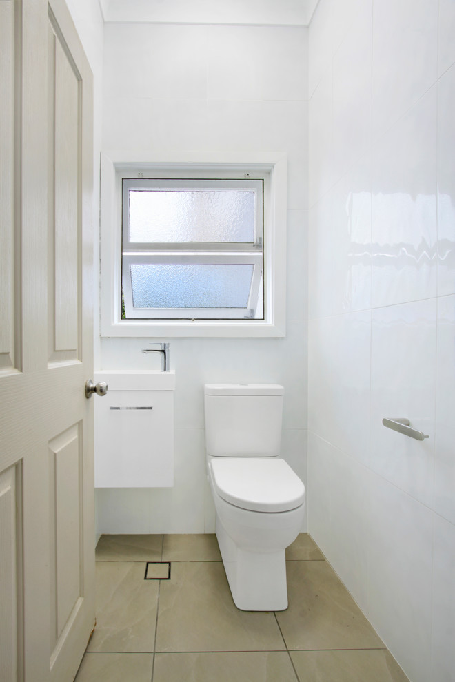 Small contemporary bathroom in Wollongong with furniture-like cabinets, white cabinets, a one-piece toilet, white tile, porcelain tile, white walls, ceramic floors and beige floor.