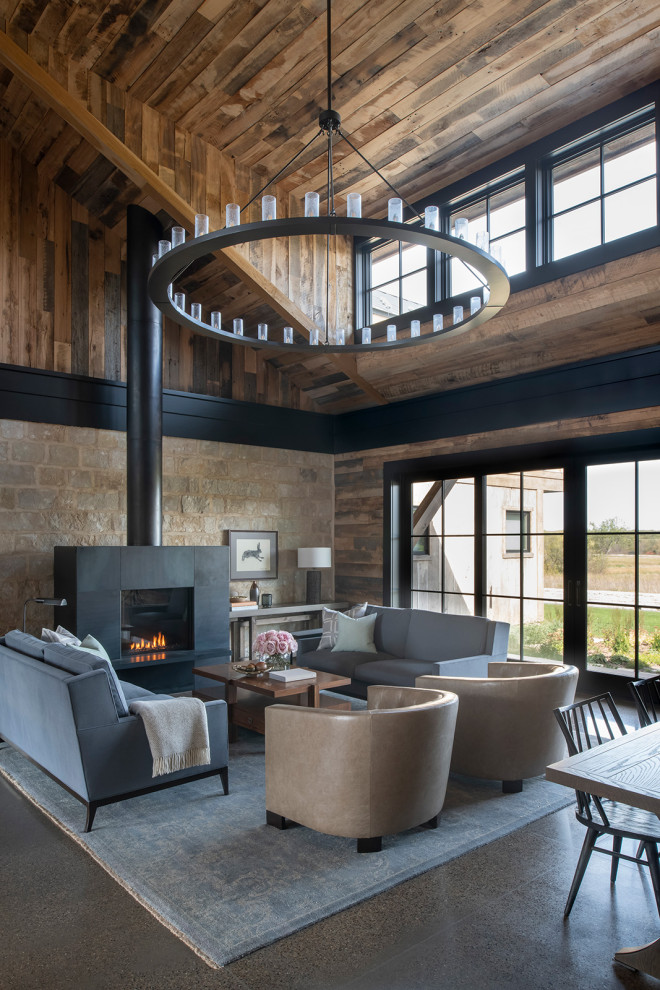 Photo of a country open concept living room in Minneapolis with concrete floors, a standard fireplace, brown walls, grey floor, vaulted, wood and wood walls.