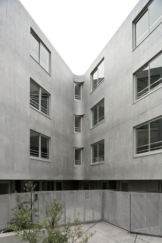 На фото: четырехэтажный, серый многоквартирный дом в стиле модернизм с