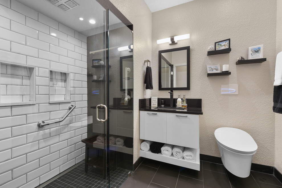 Inspiration for a small modern master bathroom in Jacksonville with flat-panel cabinets, white cabinets, an alcove shower, a wall-mount toilet, black and white tile, porcelain tile, beige walls, porcelain floors, an undermount sink, engineered quartz benchtops, black floor, a hinged shower door and black benchtops.