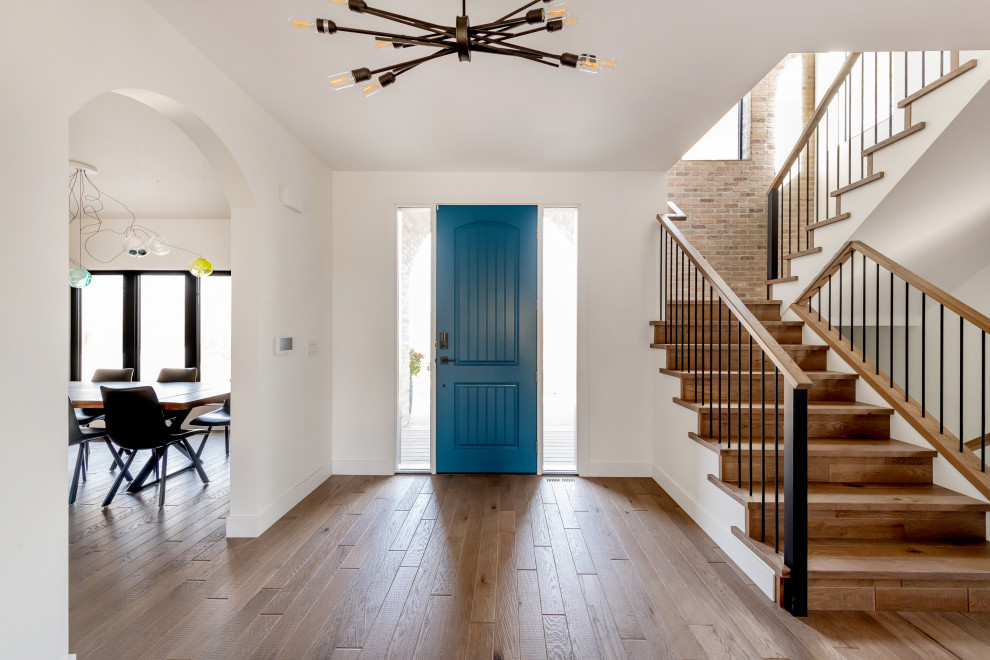 На фото: входная дверь среднего размера в стиле фьюжн с белыми стенами, паркетным полом среднего тона, одностворчатой входной дверью, синей входной дверью, коричневым полом и кирпичными стенами