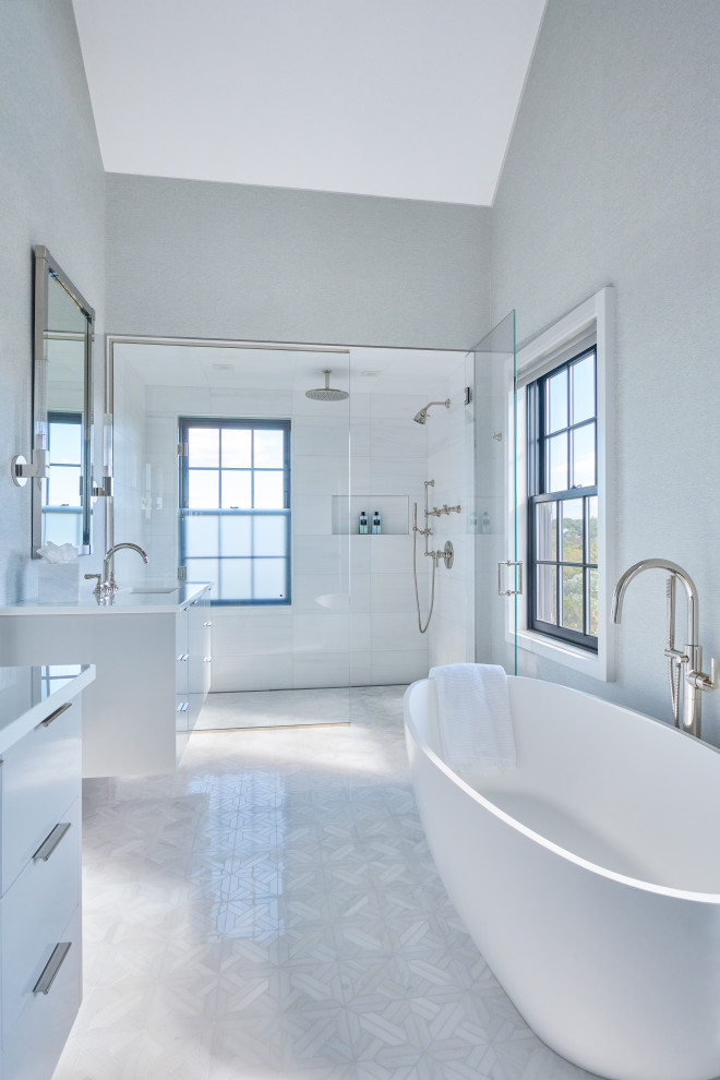 На фото: ванная комната в стиле модернизм с плоскими фасадами, белыми фасадами, отдельно стоящей ванной, душем без бортиков, серыми стенами, полом из керамогранита, врезной раковиной, столешницей из переработанного стекла, серым полом, душем с распашными дверями, белой столешницей, тумбой под две раковины и подвесной тумбой с