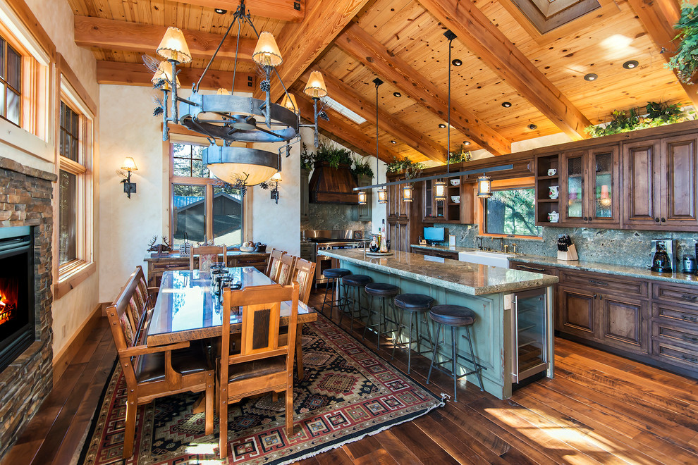Example of a mountain style medium tone wood floor kitchen design with a farmhouse sink, raised-panel cabinets, dark wood cabinets, granite countertops, stone slab backsplash and an island