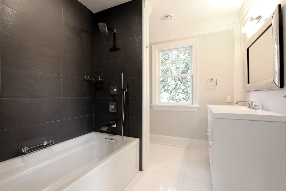 Photo of a mid-sized contemporary 3/4 bathroom in New York with flat-panel cabinets, white cabinets, an alcove tub, a shower/bathtub combo, gray tile, slate, grey walls, porcelain floors, an integrated sink, engineered quartz benchtops, white floor and white benchtops.