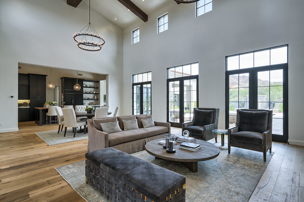 Large mediterranean open concept living room in Phoenix with brown floor, white walls, light hardwood floors, a standard fireplace and a stone fireplace surround.