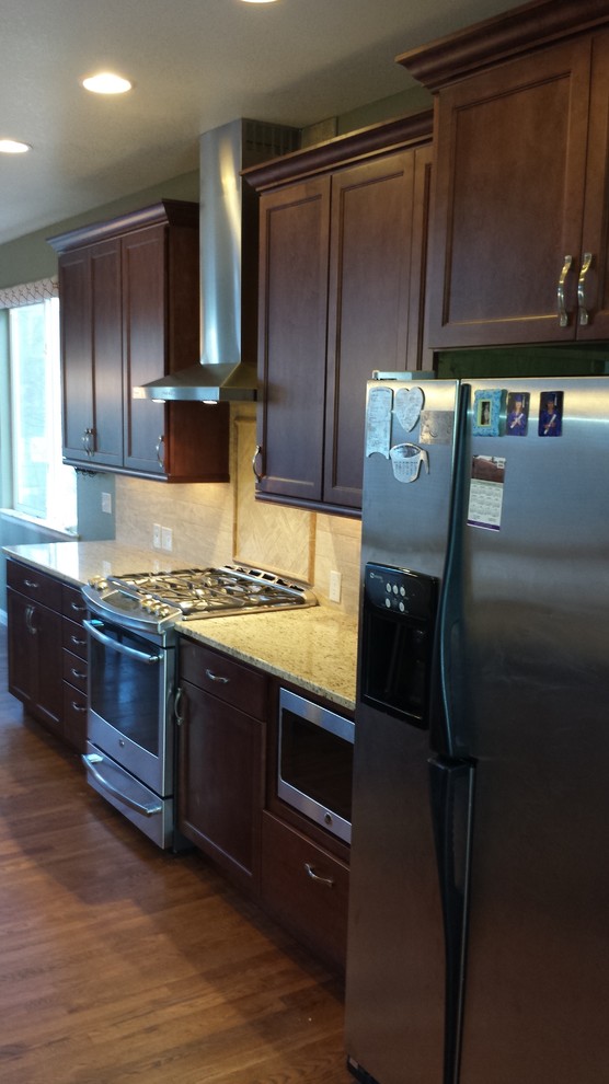 Medium tone wood floor kitchen photo in Denver with recessed-panel cabinets, dark wood cabinets and stainless steel appliances
