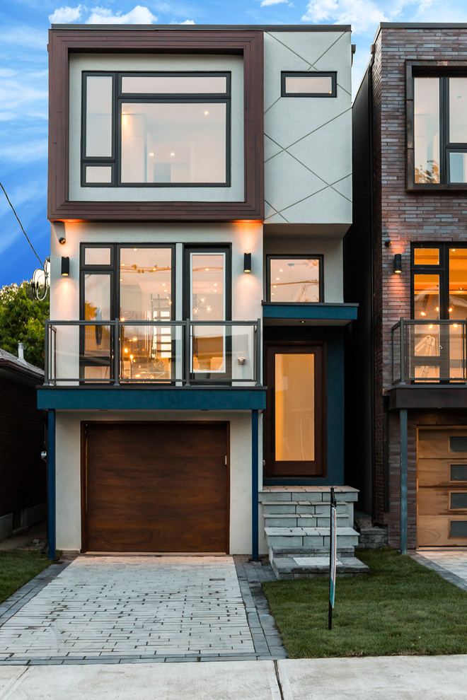 This is an example of a small modern split-level white exterior in Toronto with a flat roof.