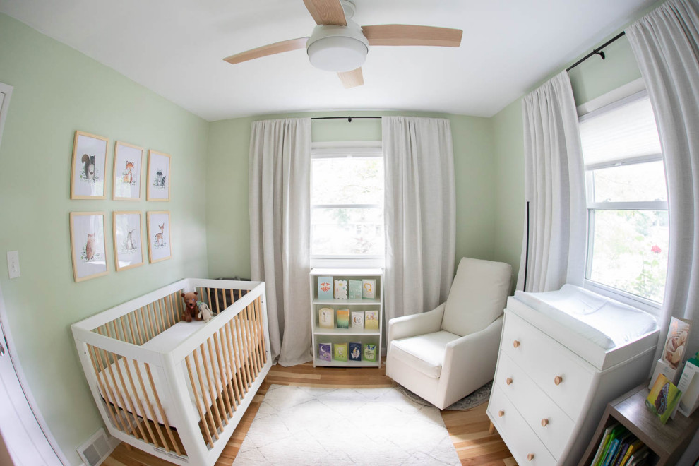 Immagine di una piccola cameretta per neonati neutra minimal con pareti verdi e parquet chiaro