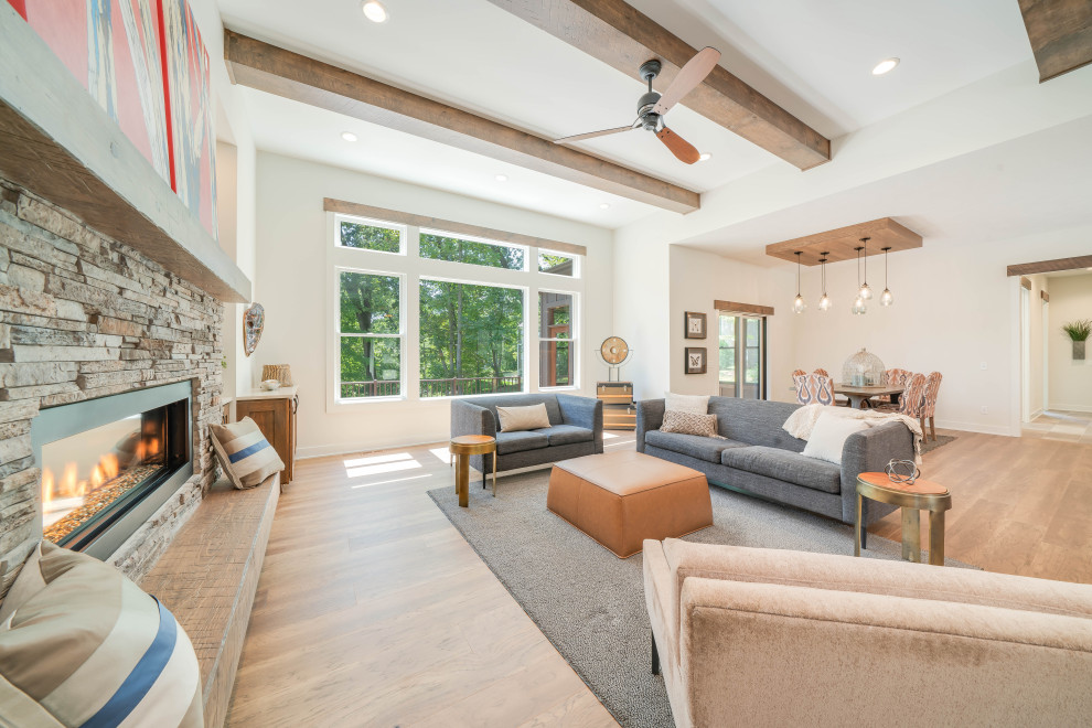 This is an example of a large eclectic open concept living room in Grand Rapids with white walls, medium hardwood floors, a standard fireplace, brown floor and exposed beam.