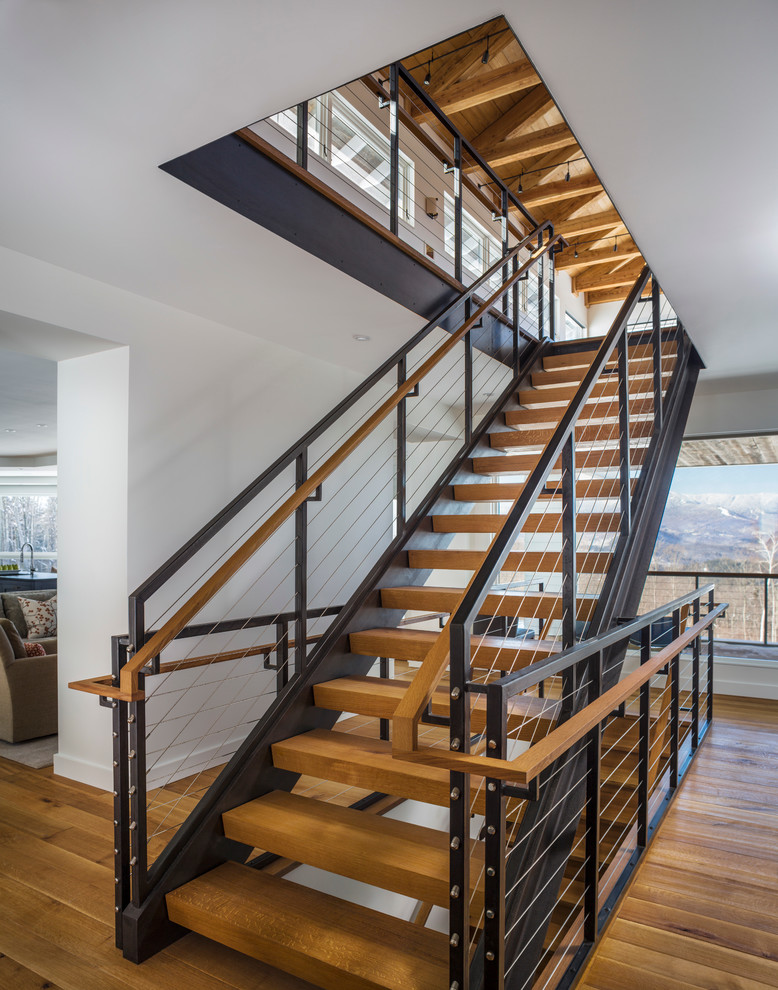 Photo of a large country wood straight staircase in Burlington with open risers and cable railing.