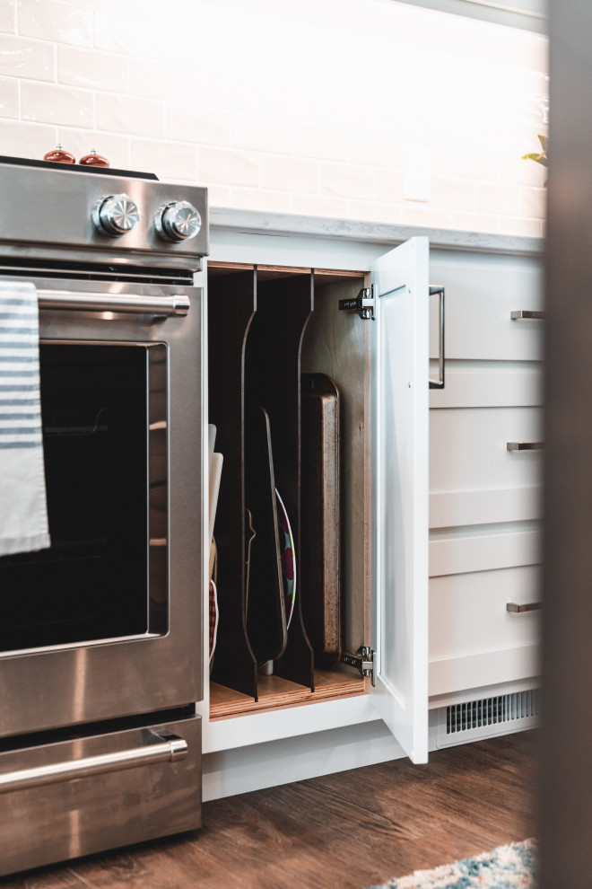 Kitchen pantry - large transitional l-shaped vinyl floor and brown floor kitchen pantry idea with an undermount sink, shaker cabinets, white cabinets, quartz countertops, gray backsplash, subway tile backsplash, stainless steel appliances, an island and white countertops