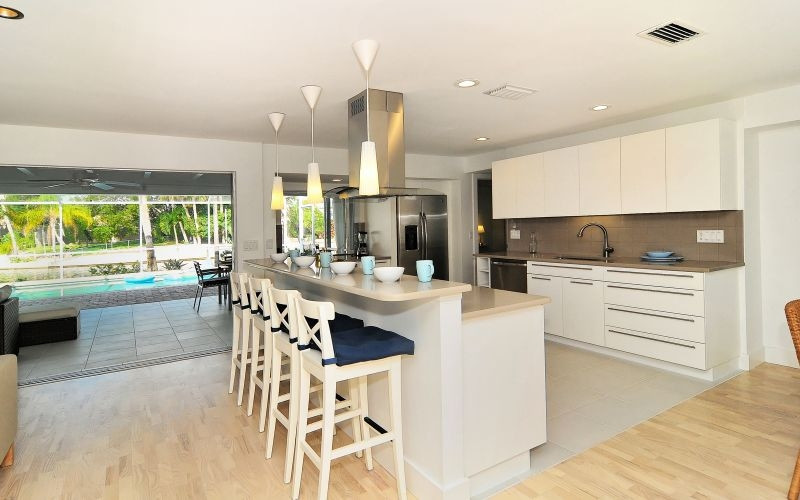 Large contemporary galley open plan kitchen in Tampa with an undermount sink, flat-panel cabinets, white cabinets, quartz benchtops, beige splashback, ceramic splashback, stainless steel appliances, porcelain floors and with island.