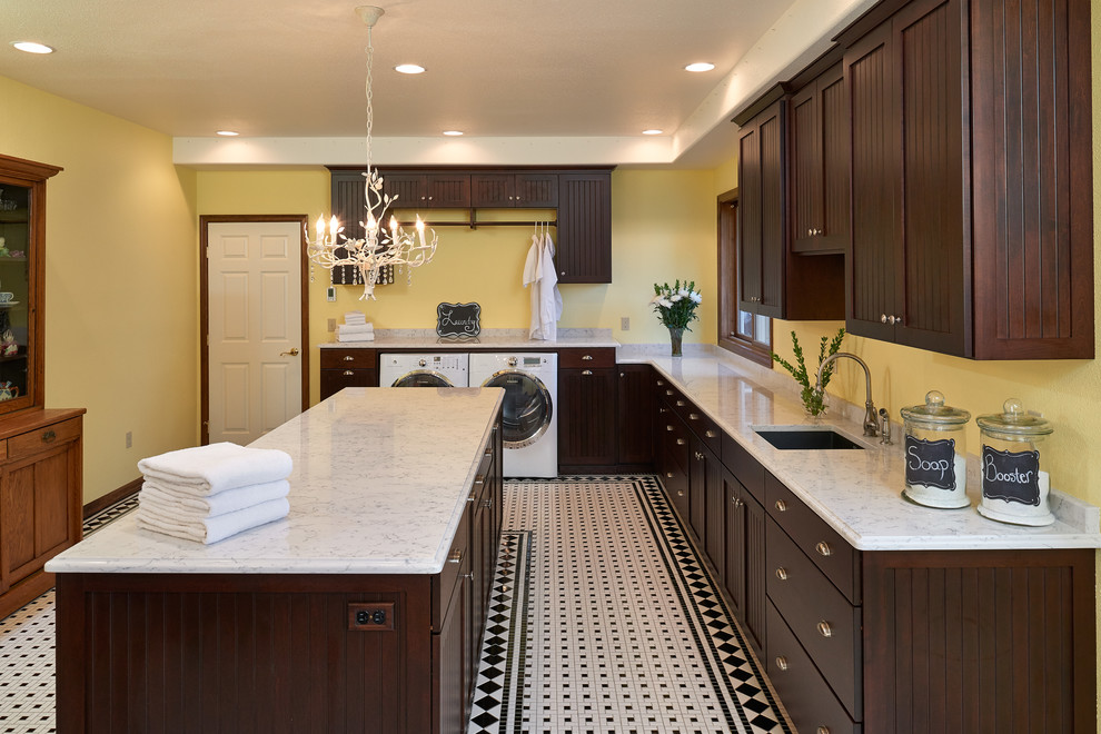 This is an example of an expansive traditional dedicated laundry room in Portland with an undermount sink, shaker cabinets, dark wood cabinets, quartz benchtops, yellow walls, porcelain floors and a side-by-side washer and dryer.