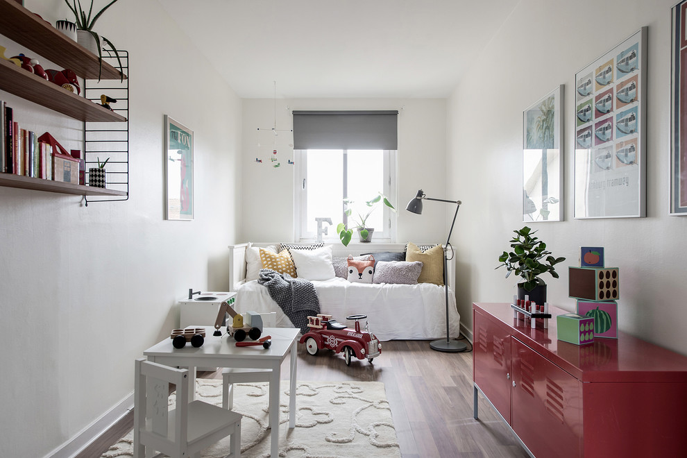 Mid-sized scandinavian gender-neutral kids' room in Gothenburg with white walls, medium hardwood floors and beige floor.