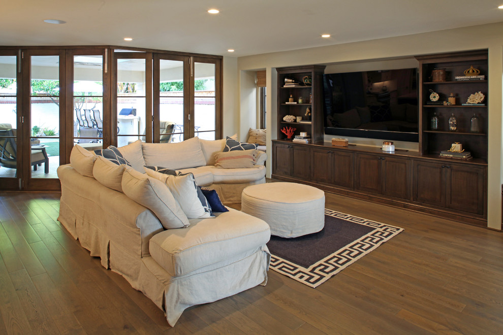 Photo of a mid-sized mediterranean open concept family room in San Diego with beige walls, medium hardwood floors and a built-in media wall.