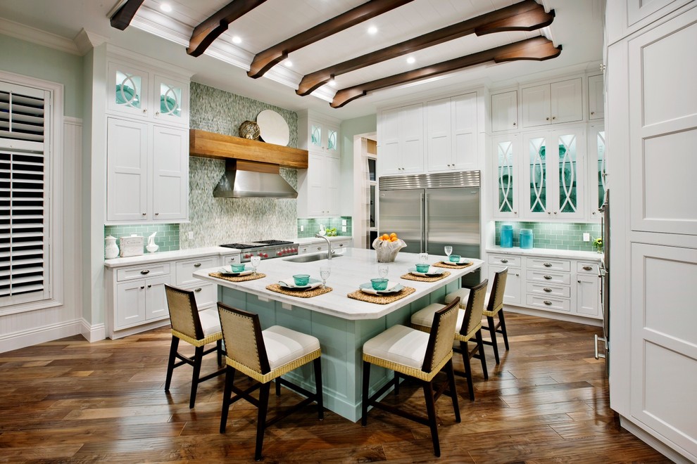 Design ideas for a mid-sized tropical u-shaped open plan kitchen in Miami with a drop-in sink, shaker cabinets, white cabinets, blue splashback, subway tile splashback, stainless steel appliances, medium hardwood floors and with island.