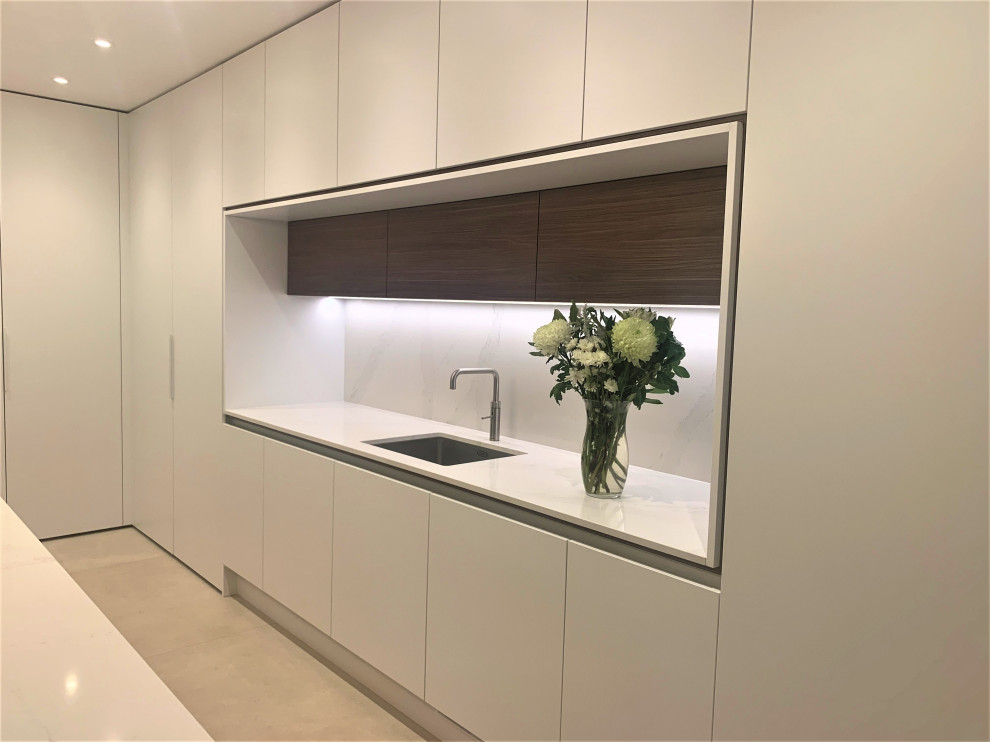 Photo of a medium sized contemporary l-shaped kitchen in Other with a single-bowl sink, flat-panel cabinets, dark wood cabinets, quartz worktops, white splashback, glass sheet splashback, stainless steel appliances, porcelain flooring, an island, grey floors and white worktops.