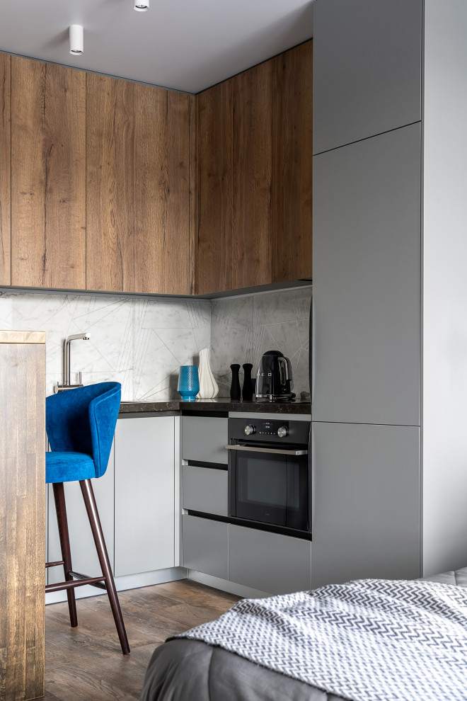 Mid-sized contemporary u-shaped open plan kitchen in Other with an undermount sink, flat-panel cabinets, grey cabinets, quartz benchtops, grey splashback, porcelain splashback, black appliances, vinyl floors, with island, brown floor, black benchtop and recessed.