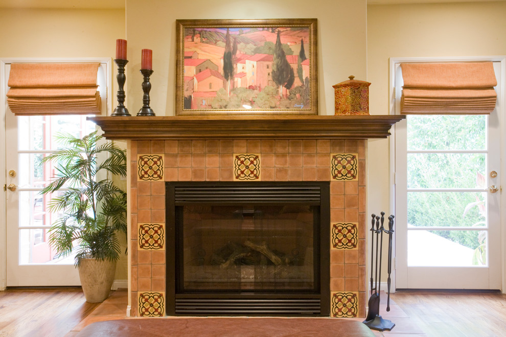 This is an example of a mid-sized mediterranean enclosed family room in Los Angeles with a home bar, medium hardwood floors, a standard fireplace and a tile fireplace surround.