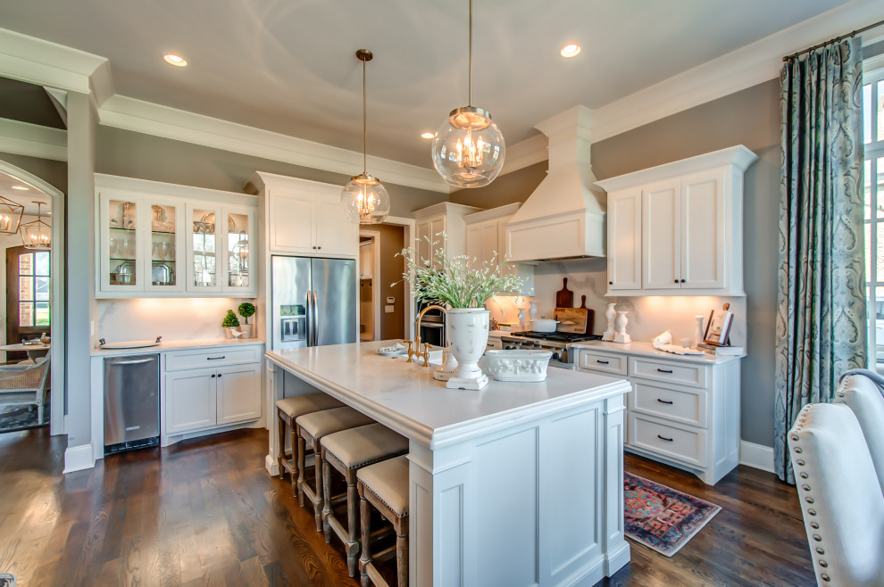 Transitional l-shaped medium tone wood floor and brown floor eat-in kitchen photo in Nashville with a farmhouse sink, beaded inset cabinets, white cabinets, white backsplash, stainless steel appliances, an island and white countertops