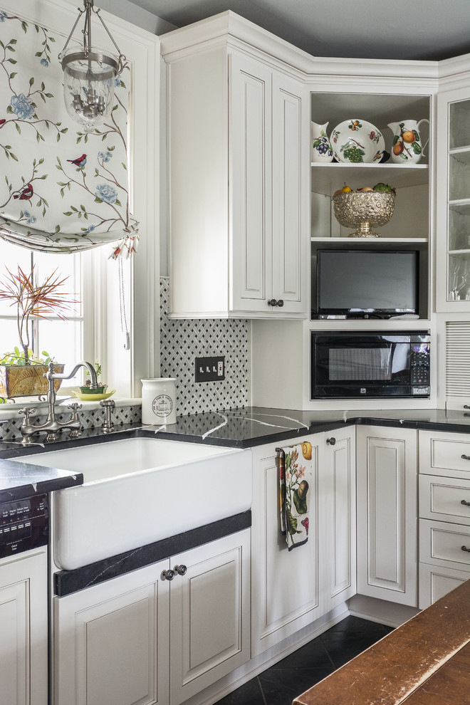 Photo of a traditional kitchen in DC Metro with a farmhouse sink, recessed-panel cabinets, white cabinets, multi-coloured splashback, black floor and black benchtop.