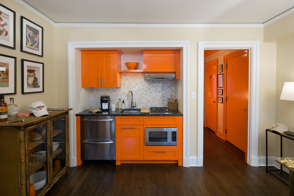 Photo of a small transitional single-wall eat-in kitchen in Philadelphia with a single-bowl sink, flat-panel cabinets, orange cabinets, granite benchtops, grey splashback, stone tile splashback, stainless steel appliances, dark hardwood floors, no island and brown floor.